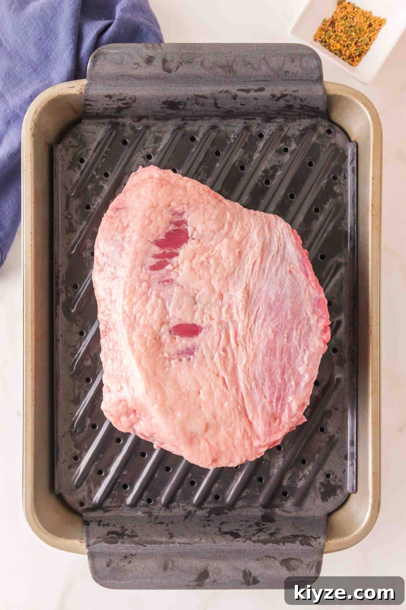 Juicy Oven-Baked Corned Beef Brisket Recipe 5 Top down view of a trimmed beef brisket on a baking rack. Hostess At Heart