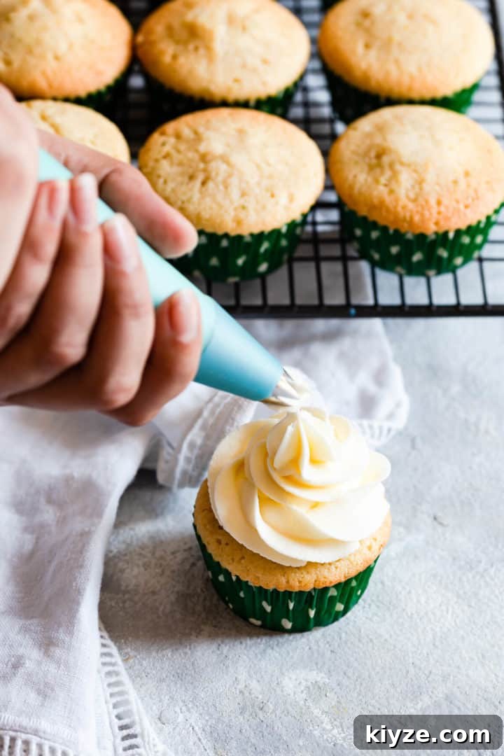 side close up at a butter icing being piped on top of a cupcake