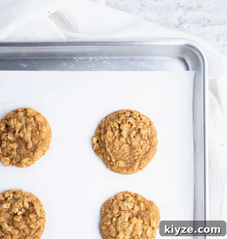 baked pumpkin oatmeal cookies on parchment paper on a silver baking sheet.