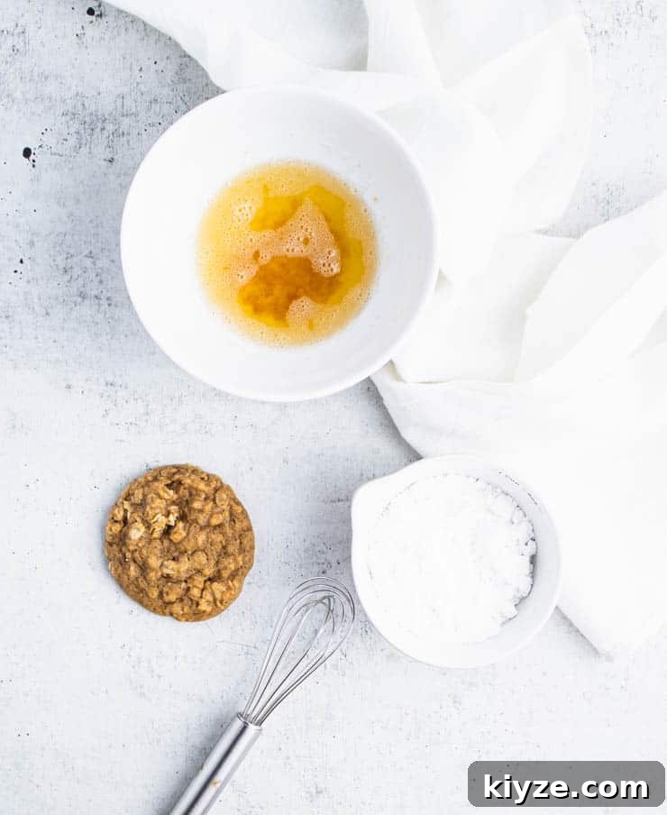 a baked pumpkin oatmeal cookie next to a bowl of browned butter and powdered sugar.