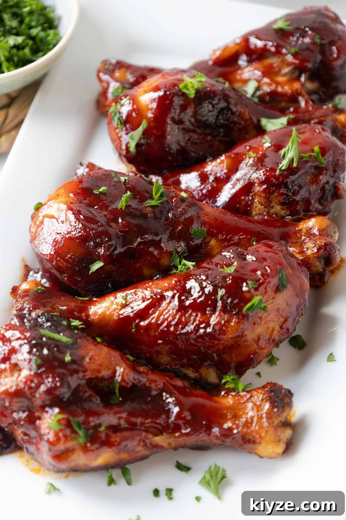 Crispy Oven-Baked BBQ Chicken Drumsticks 9 Several oven baked chicken drumsticks are arranged together and covered in a rich barbecue glaze. The sauce clings to the skin and has a shiny, slightly charred finish.