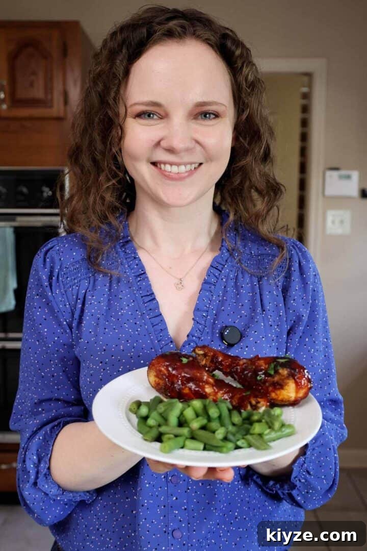 Crispy Oven-Baked BBQ Chicken Drumsticks 10 Kelsey Smith holding a plate of bbq chicken drumsticks and green beans.