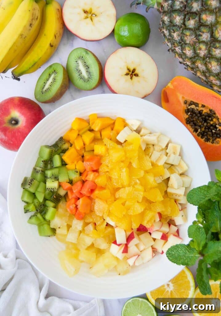 Tropical Fruit Salad with Mango, Pineapple and Coconut 4 ingredients of a tropical fruit salad recipe in a white bowl together before tossing