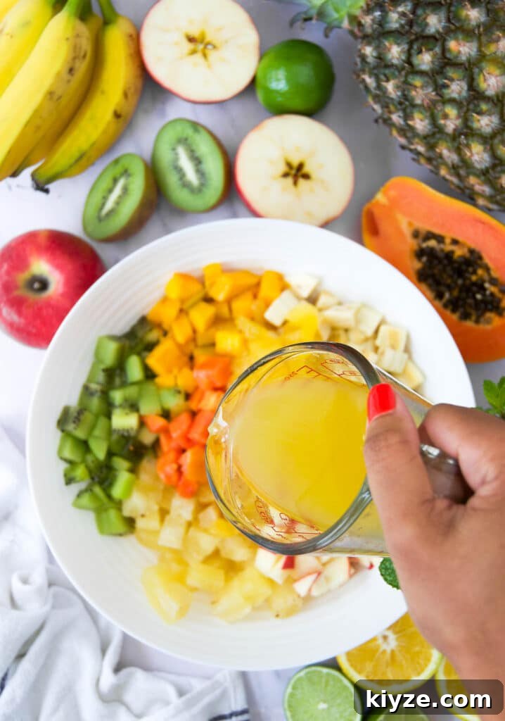 Tropical Fruit Salad with Mango, Pineapple and Coconut 5 orange juice drizzles on top of a bowl of tropical fruit