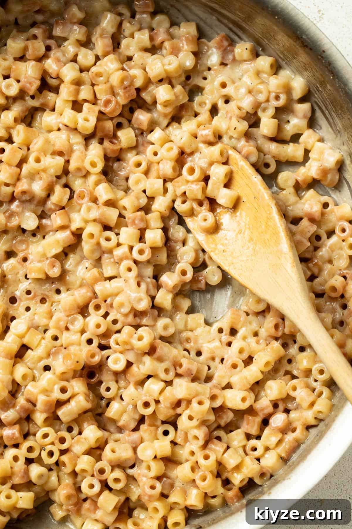 Garlic butter pasta in a stainless steel pan with a wood serving spoon. 