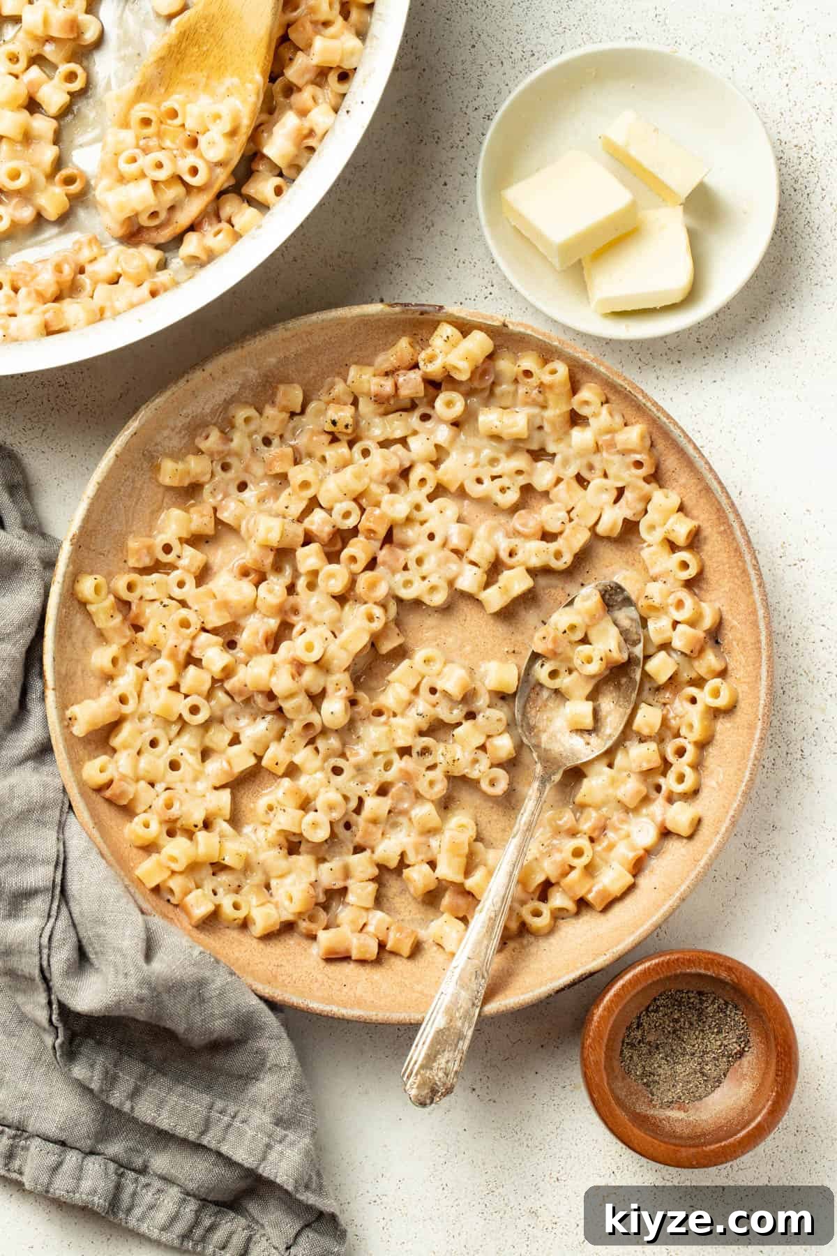 Serving the buttered pasta in a bowl next to bread and salt and pepper.