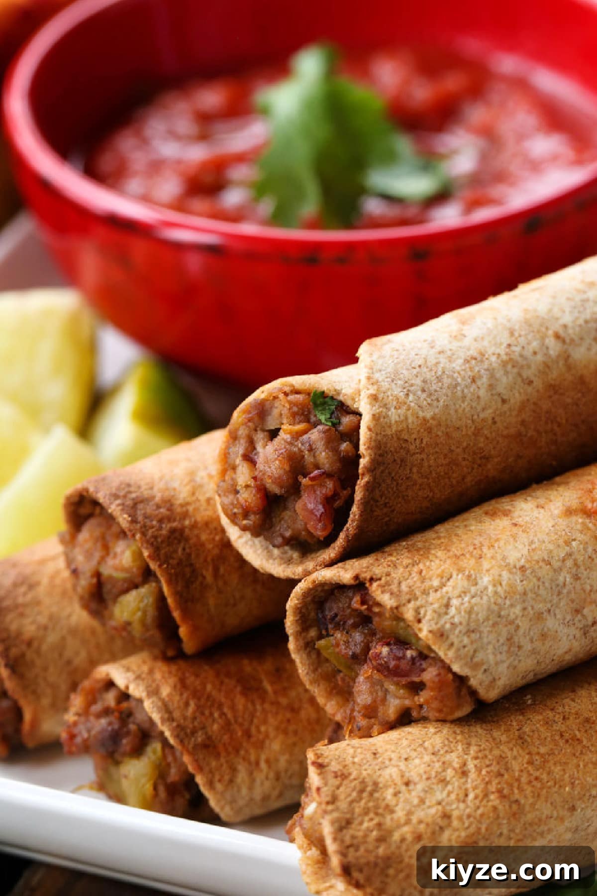 Crispy beef taquitos ready to serve beef taquitos stacked on a plate with salsa