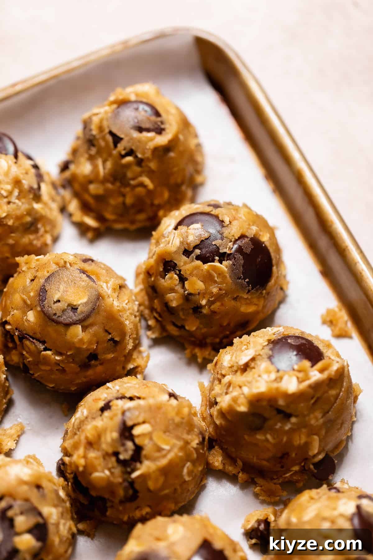 Brown Butter Oatmeal Chocolate Chip Cookies Recipe 6 Scooped cookie dough balls on a parchment-lined baking sheet.