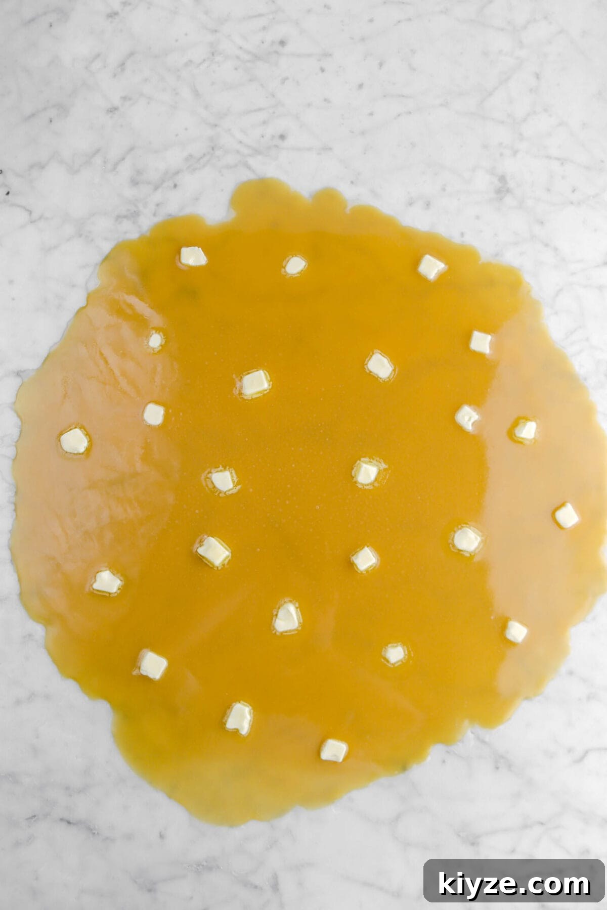 Old-Fashioned Maple Fudge Recipe 10 butter dolloped onto caramel on marble surface.