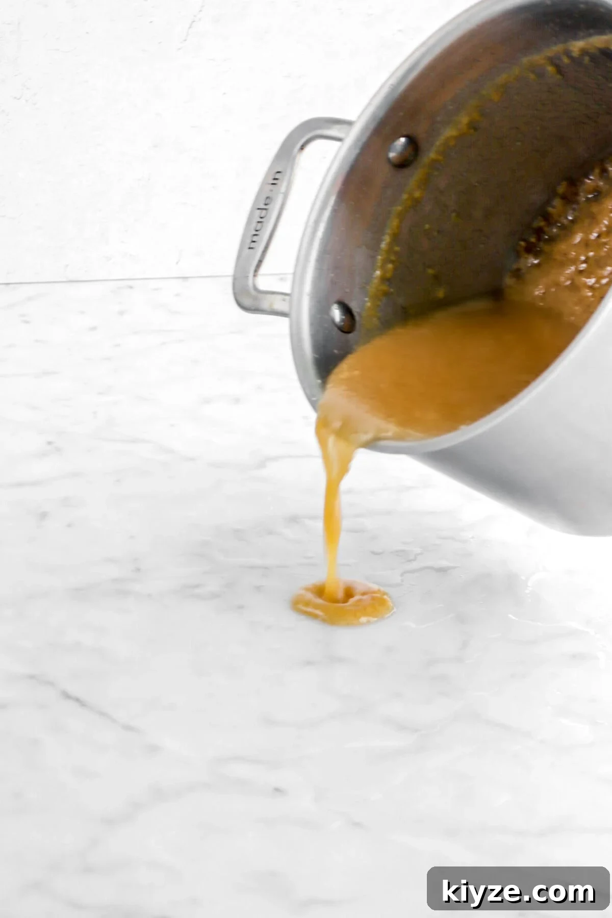 Old-Fashioned Maple Fudge Recipe 9 caramel being poured onto wet marble counter.