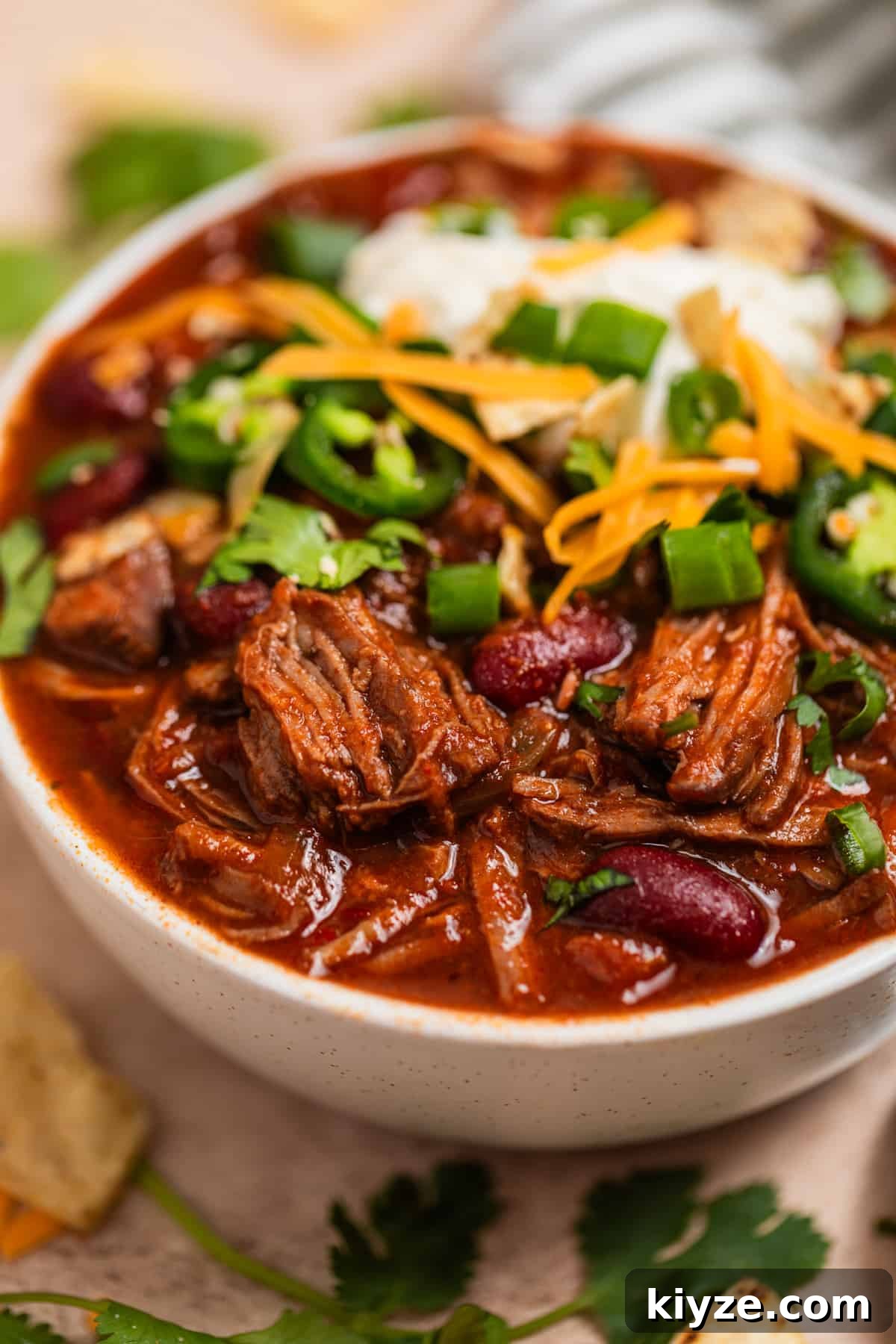 Slow Cooker Shredded Beef Chili Recipe 3 Bowl of crockpot chili topped with sour cream, cheese and other toppings.
