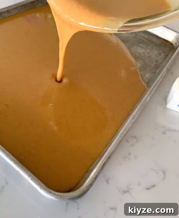 pouring pumpkin bars batter into sheet pan