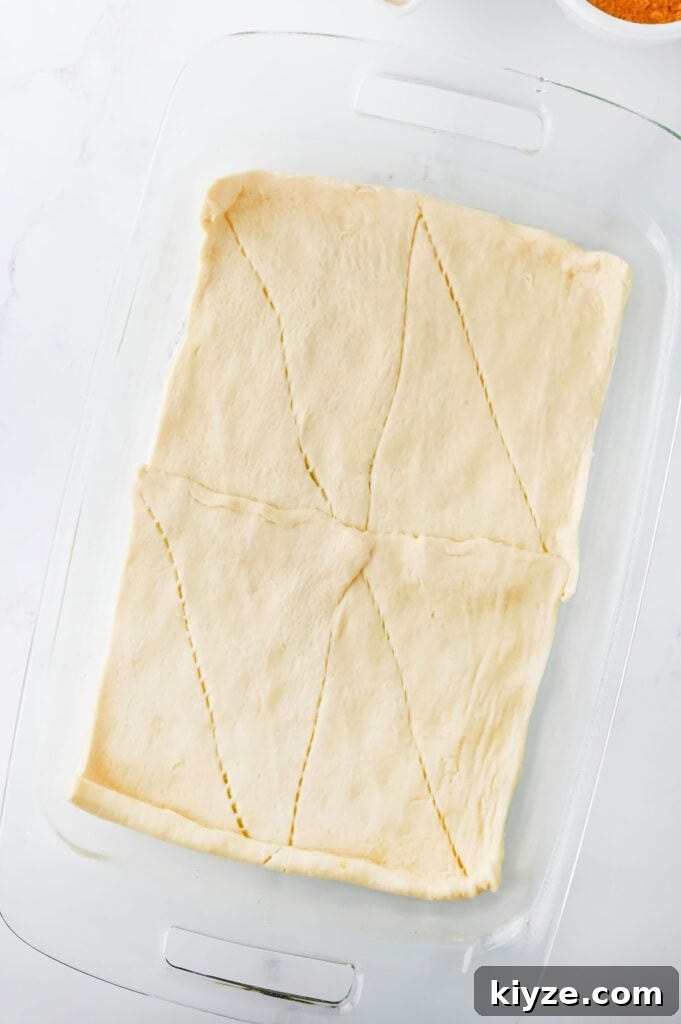 crescent roll dough in bottom of a glass casserole dish