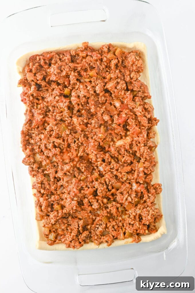 ground beef over crescent roll dough in glass casserole dish