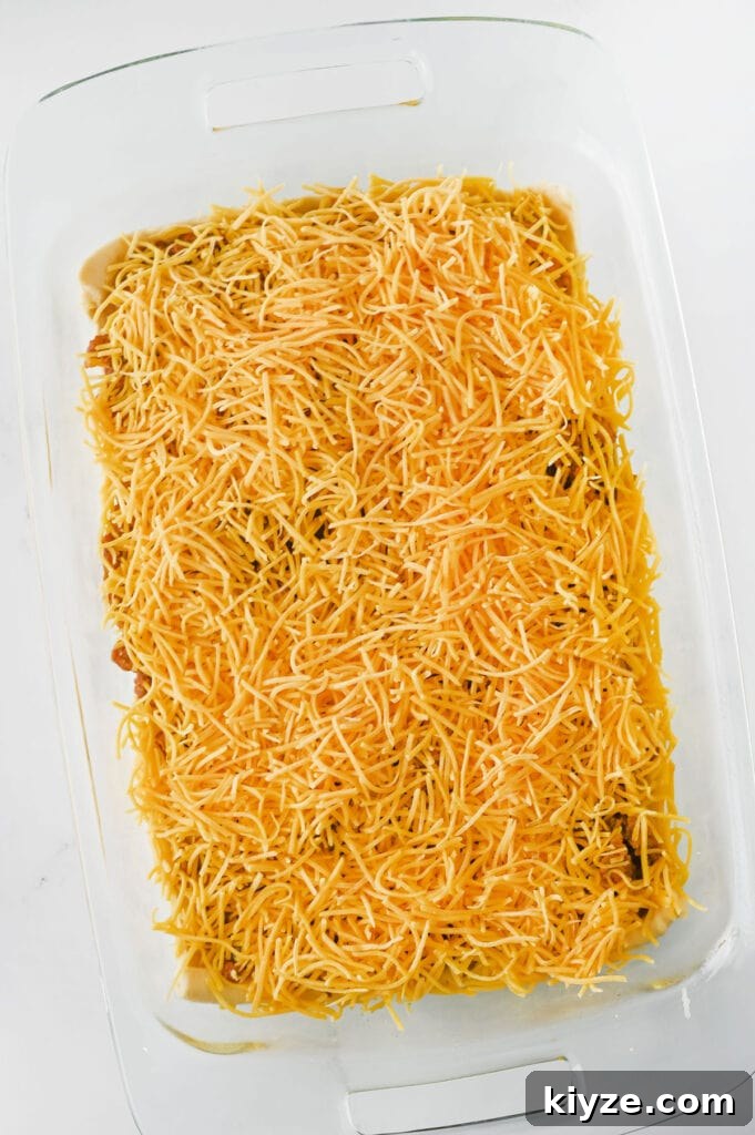 crescent taco bake before baking, topped with shredded cheese