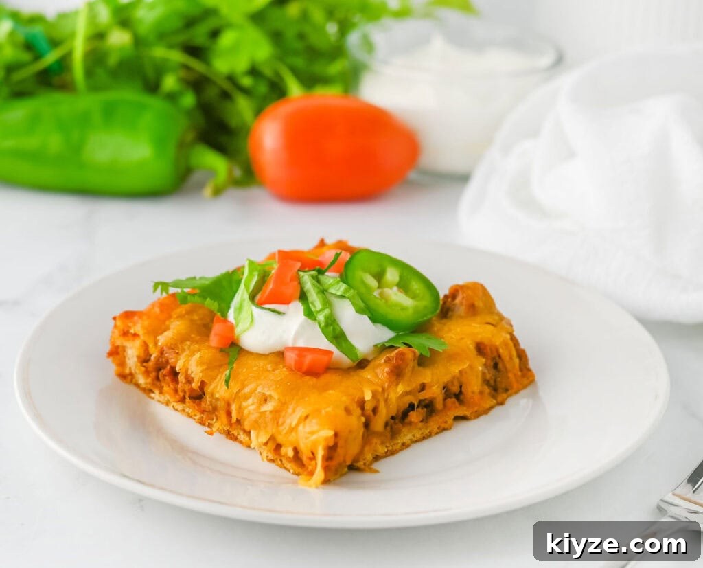 portion of crescent taco bake on white plate topped with sour cream and slice of jalapeno