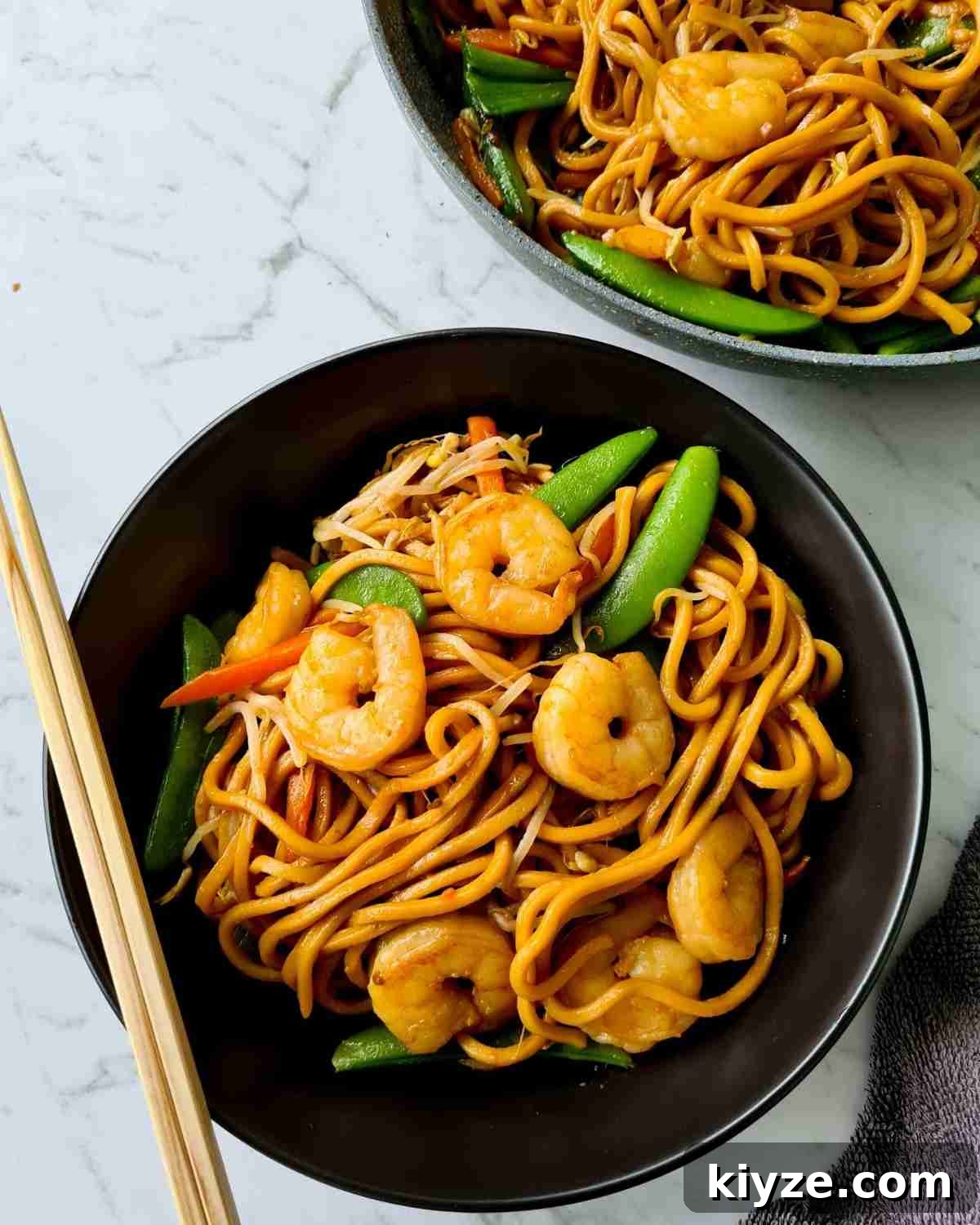 Wok Fried Prawn Noodles with Garlic and Chili 5 Noodle stir fry in a black bowl with a pair of chopsticks sat on top of the bowl