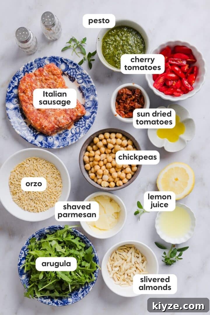 Fresh Pesto and Orzo Salad with Cherry Tomatoes and Basil 3 Ingredients for pesto and orzo salad with Italian sausage displayed in small bowls on a white marble counter.