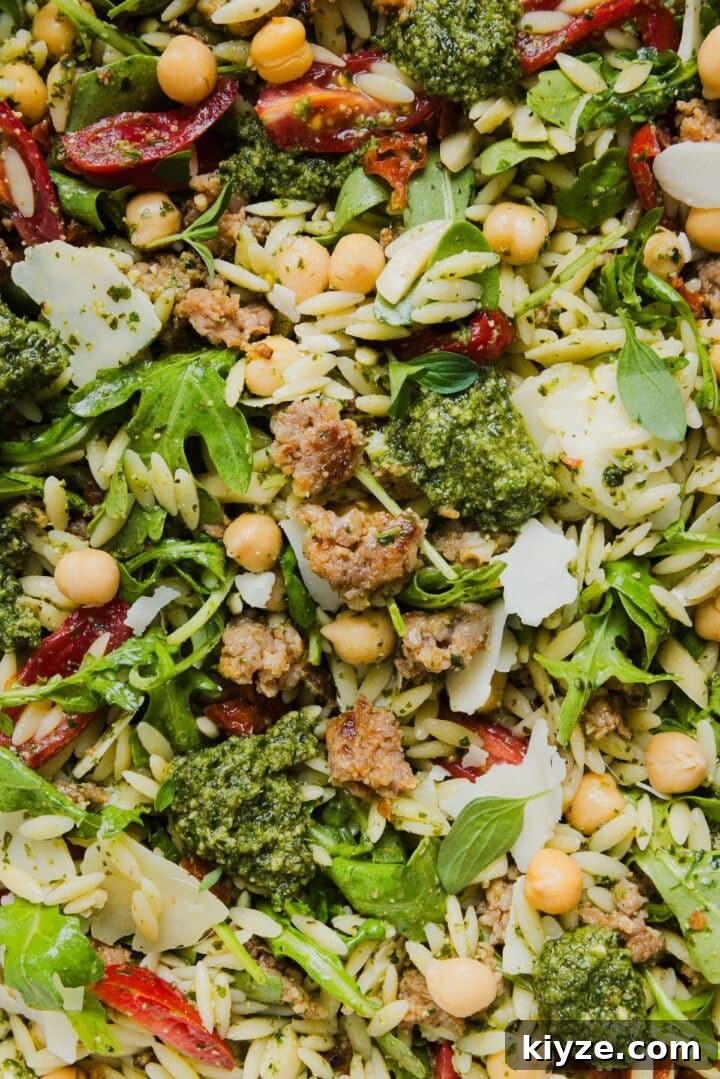 Fresh Pesto and Orzo Salad with Cherry Tomatoes and Basil 8 Close-up photo of pesto and orzo salad with Italian sausage in a large mixing bowl.