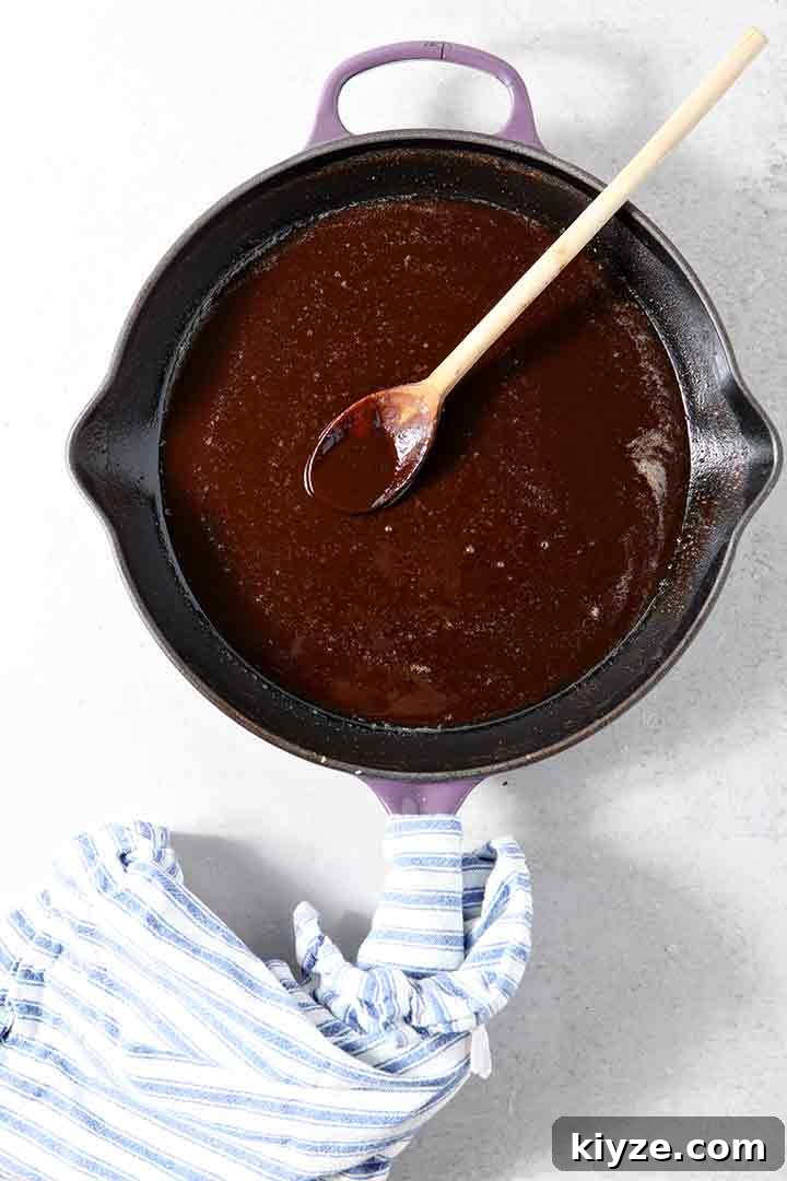 A dark roux is shown on a light background in a skillet