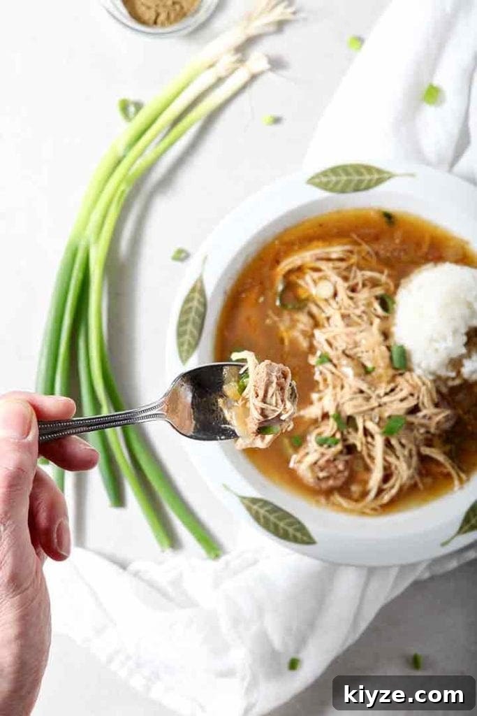 A man lifts a spoonful of Chicken and Sausage Gumbo out of the bowl