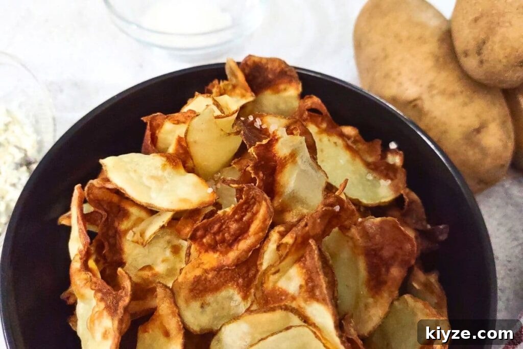 ninja air fryer potato chips in a bowl next to two fresh potatoes
